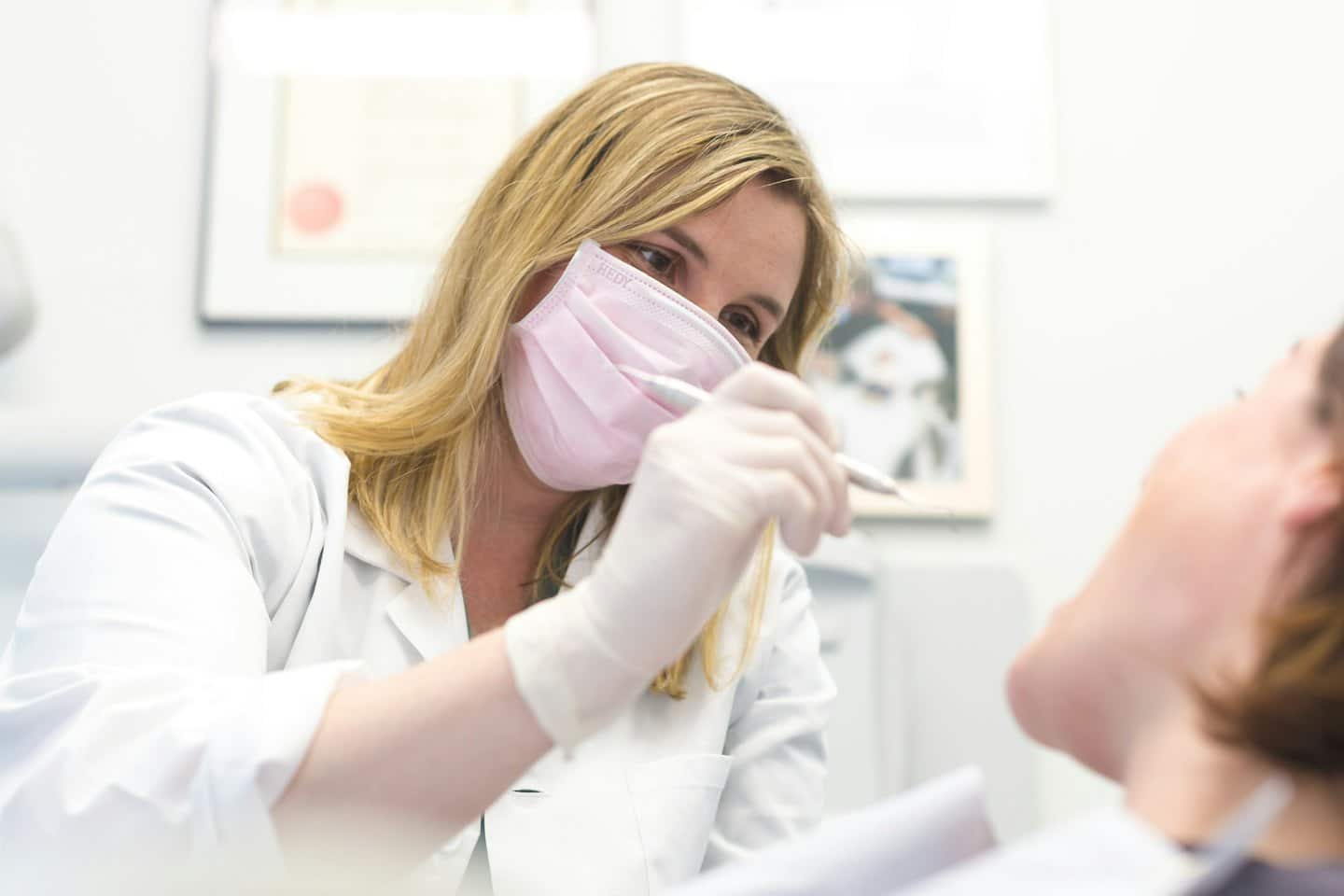Zahnarzt untersucht mit einem Werkzeug die Zähne eines Patienten.
