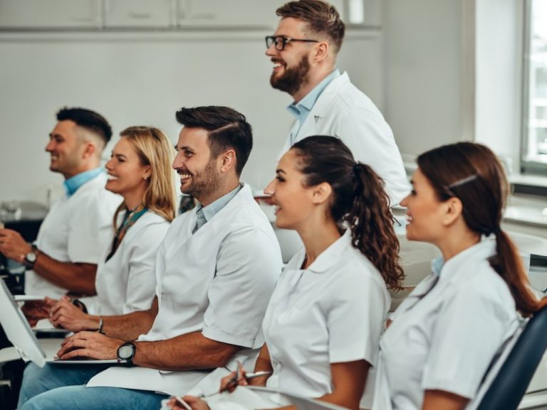 Gruppe von Fachleuten in weißen Laborkitteln während einer Besprechung.